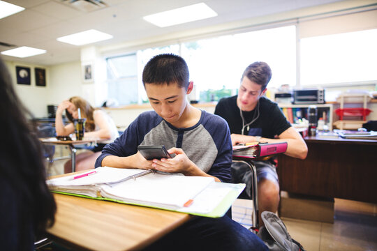 Real high school teenage student working with math calculator in classroom