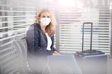 Eine Frau mit Maske wartet am Bahnhof, Maskenpflicht in der Öffentlichkeit 