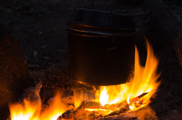 fire burns in the campaign. pot of tea by the fire.