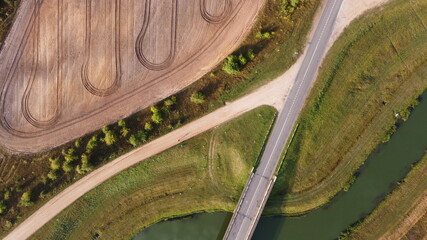 Top view of asphalt road bridge over the river in the fields