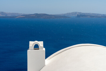 White roof with chimney on the Caldera at Oia, Santorini island, Greece. beautiful blue seascape with volcano in the background