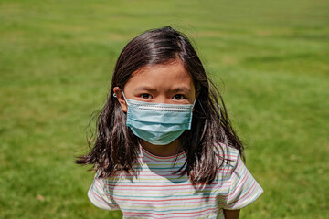 Asian young kid wearing a mask in the park