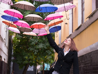 Smiling beautiful woman walking at a street with multi colored umbrellas. Romantic girl pretending touch umbrella and fly on arrow streets.Traveler woman in Italy enjoing trip
Dream and love concept