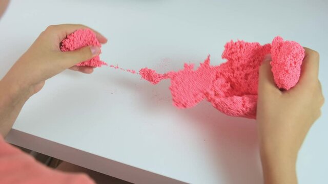 A boy playing with slime, crushing squizing and crumpling pink plasticine, gum for hands with small balls inside, anti stress and relaxing game, close up