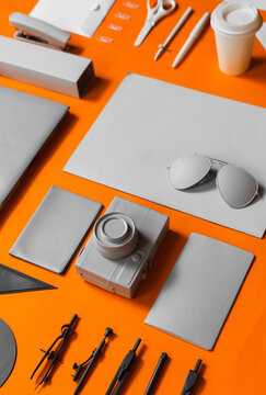 Office supplies in white grey and black color arranged on orange backgorund.