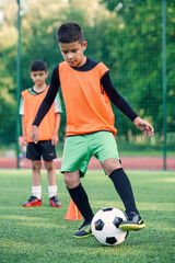 Soccer player kicking ball on field. Soccer players on training session. Teen footballer kicking...
