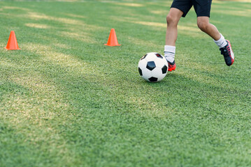 Soccer player kicking ball on field. Soccer players on training session. Close up footballer feet kicking ball on grass.