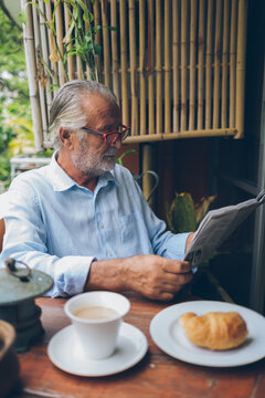 Senior Man Reading Newspapers and Having Breakfast