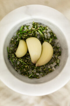 Chopped rosemary, sea salt and whole garlic cloves in a mortar