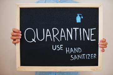Quarantine use hand sanitizer. Coronavirus concept. Boy hold inscription on the board.