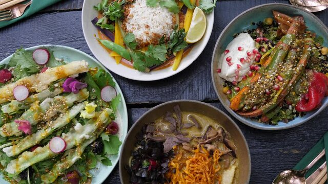 Serving two plates with healthy organic vegan meals to the black wooden table
