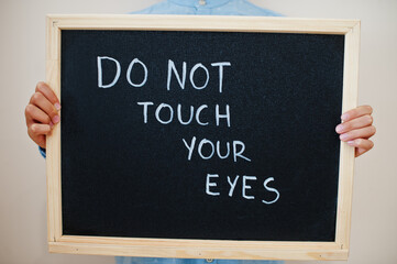 Do not touch your eyes. Coronavirus concept. Boy hold inscription on the board.
