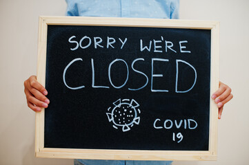 Sorry we're closed Covid-19. Coronavirus concept. Boy hold inscription on the board.