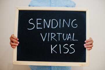 Sending virtual kiss. Coronavirus concept. Boy hold inscription on the board.