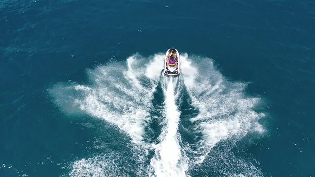 Aerial drone video of jet ski watercraft cruising in high speed performing stunts in tropical exotic island
