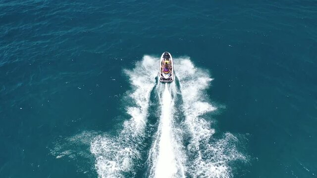 Aerial drone video of jet ski watercraft cruising in high speed performing stunts in tropical exotic island