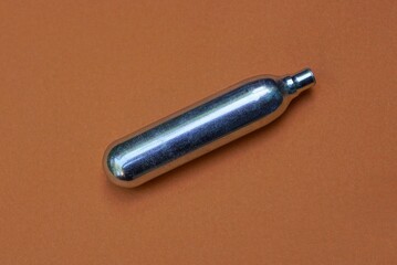 one gray metal cylinder for pneumatic weapons lies on a brown table