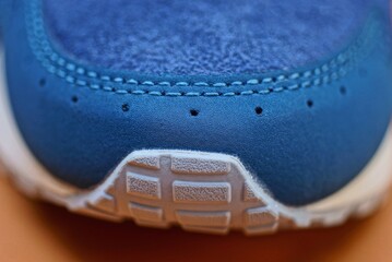 one blue white suede and leather sneaker lies on a brown table