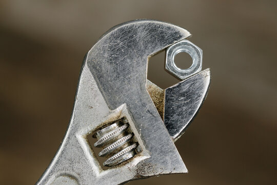Old adjustable spanner or wrench gripping a hexagonal nut.