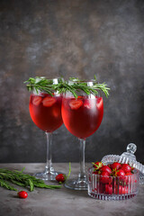 Rose champagne with strawberries and rosemary. Alcoholic cocktail in glasses.