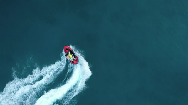 Aerial drone video of jet ski watercraft cruising in high speed performing stunts in tropical exotic island