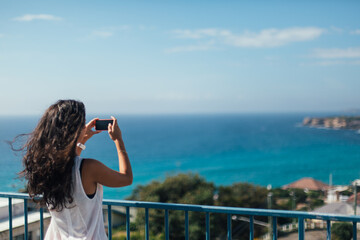Woman taking picture of the sea coast with the phone