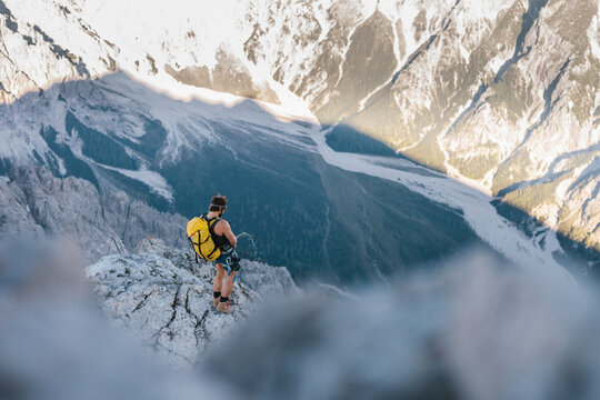 male climber peeing at the edge down the mountain
