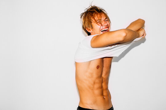 Smiling Young Man Removing T Shirt .