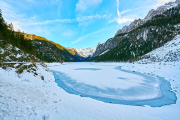 Beautiful Gosausee lake landscape with Dachstein mountains, forest, clouds and snow in Austrian Alps