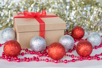 Christmas gift and new year decorations. Christmas composition of silver and red balls,  gift box, beads and glitter garland on white background.