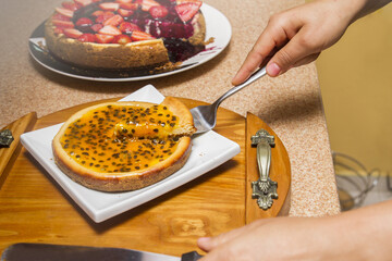 one female hand with spoon taking or serving a cake slice in house kitchen