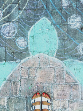 A woman feet looking down on a chalk drawing of a turtle.
