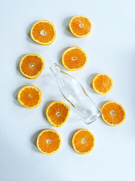Empty bottle and slices of an orange on a white table
