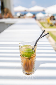 Cuba libre cocktail on a white table with beach in background