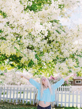blonde girl yelling for joy in front of showering floral tree