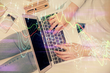 Double exposure of woman hands working on computer and forex graph hologram drawing. Top View. Financial analysis concept.