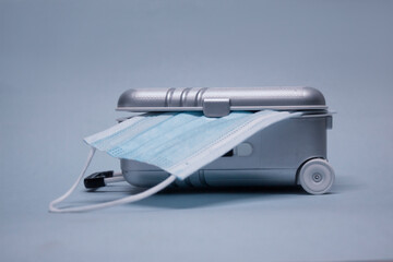 Time to travel. The concept of safe rest during a pandemic Covid-19 Coronavirus. Suitcase for travel with a medical mask.