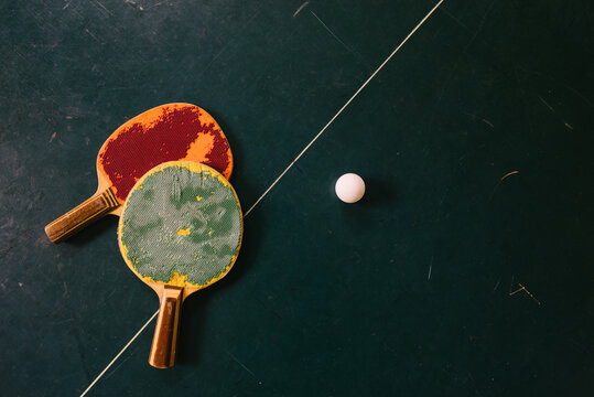 Pair of run down ping pong racketes and ping pong ball from above