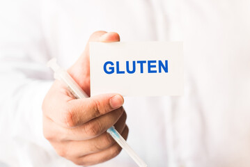 Word gluten on a white background with a syringe in hand. Medicine concept