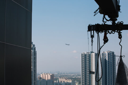 An airplane flies over the city as viewed from the rooftop of a building