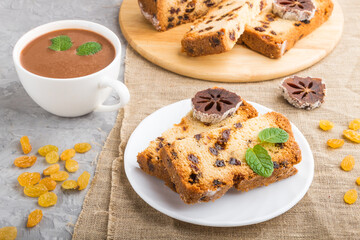Homemade cake with raisins, dried persimmon and a cup of hot chocolate on a gray concrete background. side view.