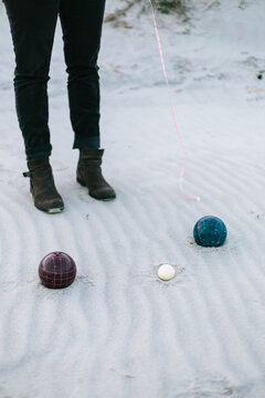 Two different bocce game balls in sand with measuring tape