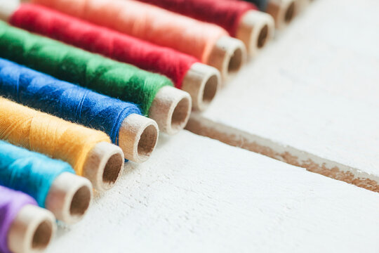 Detail shot of colorful threads on white wooden background