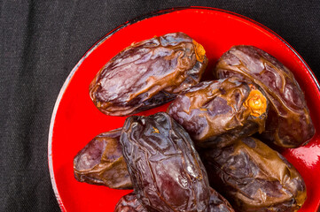 Big luxury dried date fruit in bowls on the dark surface, kurma ramadan kareem concept, close up.
