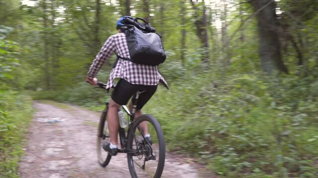 Man ride bicycle through forest, collecting trash. Trendy sports programs plogging that help preserve environment. Pollution. Ecological problem. Plastic ban awareness, national cleaning day concept.