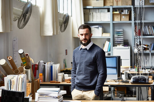 Confident Businessman Standing At Office Desk