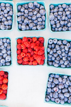 Pints filled with fresh whole blueberries and raspberries at market