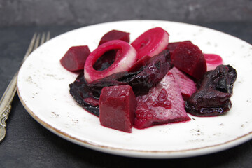 Herring with beets and dried mushrooms on a white plate. Closeup