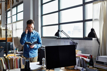 Businessman Reading Diary While On Call In Office