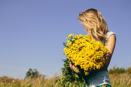 Young woman holding big bouquet of wildflowers